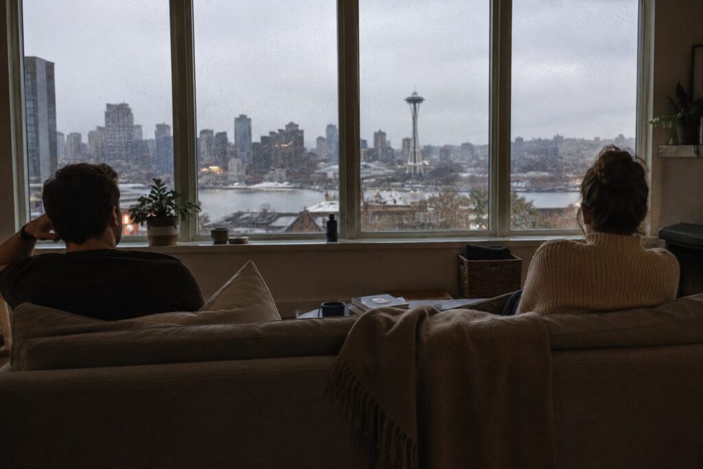 Signs your marriage is in trouble: a couple sitting apart in silence looking out at the Seattle skyline